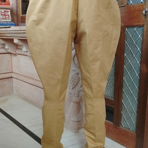 May include: A pair of brown riding breeches with a belt loop and a belt. The breeches are made of a smooth, cotton fabric.