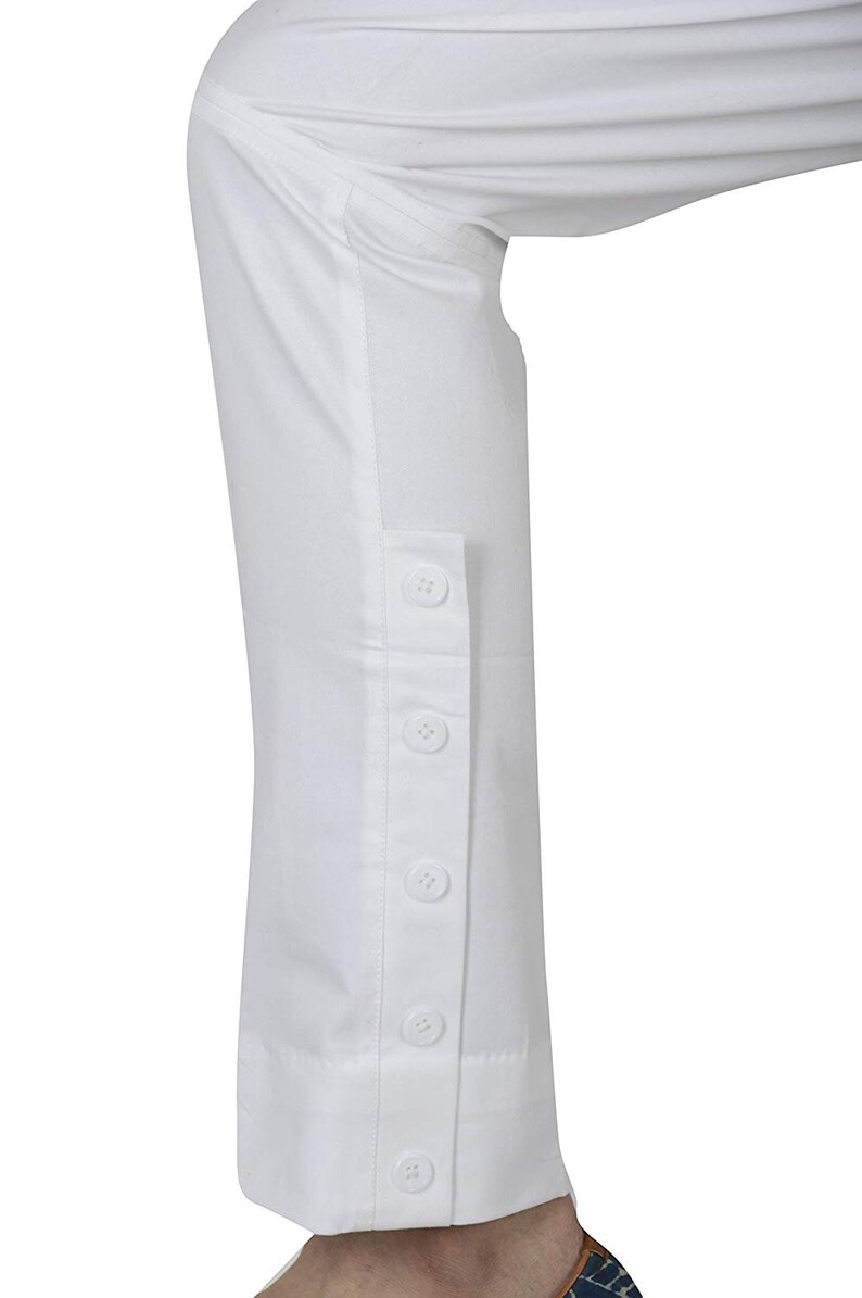 May include: White pants with a button detail on the side of the leg.