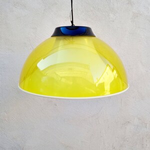 May include: A yellow dome-shaped pendant light with a black and blue trim. The light is hanging from a white ceiling.