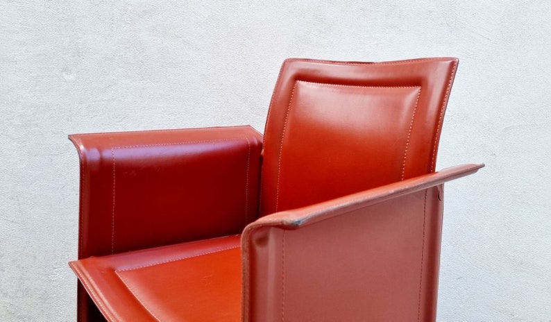 May include: A red leather armchair with a high back and a curved armrest. The chair has a simple, modern design.