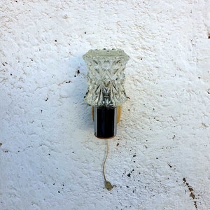 May include: A vintage wall sconce with a clear glass shade featuring a diamond pattern. The sconce has a chrome finish and a gold base.