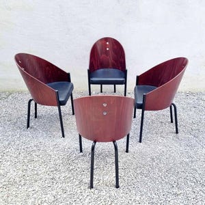 Peut inclure: Quatre chaises en bois avec des pieds en métal noir et des sièges en tissu noir. Les chaises sont disposées en cercle sur une surface de gravier.
