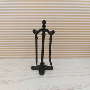 May include: Black metal fireplace tool holder with three tools. The holder has a decorative base and a curved top.