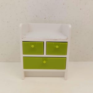 May include: White dresser with three green drawers and a white top. The dresser has a simple design with rounded edges.