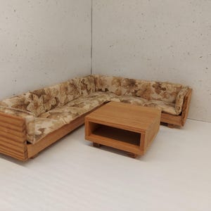 Könnte beinhalten: Ein Eck-Sofa aus Holz mit einem floral gemusterten Stoffbezug und einem passenden Holz-Couchtisch mit einem Regal.