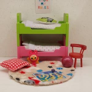 May include: A miniature bedroom set with a bunk bed, rug, and accessories. The bunk bed is green and pink, with white bedding. A red chair, a ball, and a game are on the rug. A sign on the wall reads "MY ROOM MY RULES."