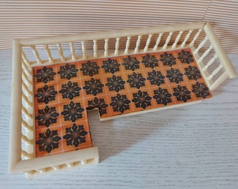 May include: A white wooden dollhouse balcony with a black and orange patterned floor. The balcony has a white railing with vertical spindles.