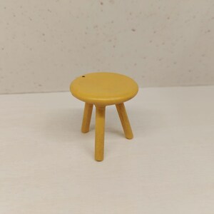May include: A small, yellow wooden stool with three legs.