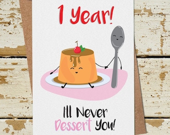 Op de afbeelding: Een witte kaart met een cartoonillustratie van een puddingbeker die hand in hand staat met een lepel. De tekst op de kaart luidt "1 jaar! Ik zal je nooit in de steek laten!"