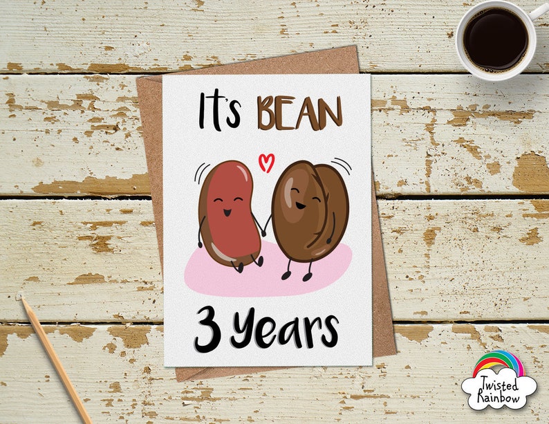 May include: A white card with the text "It's Bean 3 Years" and a cartoon image of a red bean and a brown coffee bean holding hands. The beans have happy faces and the coffee bean has a swirl above its head.