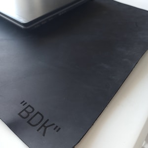 May include: Black leather desk mat with the text "BDK" embossed in the center.