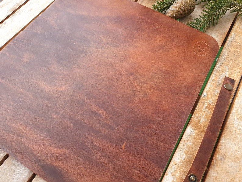 May include: A brown leather desk mat with a subtle embossed design. The mat is on a wooden surface.