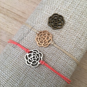 May include: Three friendship bracelets with different colored cords and metal flower charms. The charms are silver, gold, and bronze.