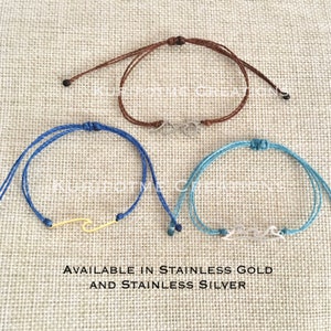 May include: Three adjustable friendship bracelets with different charms. The first bracelet is brown with a silver infinity symbol charm. The second bracelet is blue with a gold wave charm. The third bracelet is light blue with a silver wave charm.  AVAILABLE IN STAINLESS GOLD AND STAINLESS SILVER