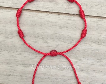 May include: Red string bracelet with knotted beads. The bracelet is adjustable with a sliding knot.