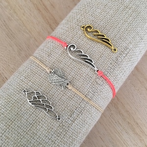 May include: Four bracelets with different silver and gold angel wing charms. Two bracelets are coral red and two are beige.