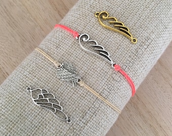 May include: Four bracelets with different silver and gold angel wing charms. Two bracelets are coral red and two are beige.