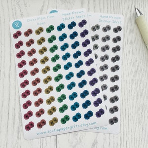 May include: Two sheets of stickers featuring hand-drawn pom poms in various colours. The first sheet has a rainbow of colours, while the second sheet has shades of grey. The sheets are labelled "Hand Drawn Sticker Sheet" and "Cheer/Pom Pom Icons".