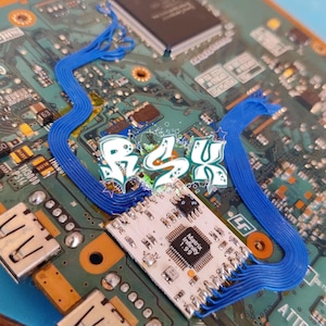 K&ouml;nnte beinhalten: Nahaufnahme einer Leiterplatte mit blauen Flachbandkabeln und einem kleinen wei&szlig;en Chip mit der Aufschrift "Matrix Infinity 1.99".