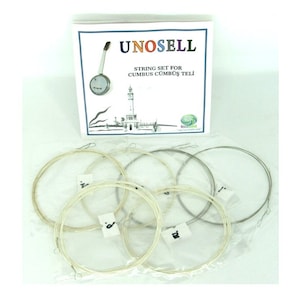 Op de afbeelding: Een set van zes snaren voor een Cumbus, een Turks snaarinstrument. De snaren zijn verpakt in doorzichtige plastic zakjes en genummerd. De verpakking bevat een klein doosje met de merknaam "UNOSELL" en de tekst "STRING SET FOR CUMBUS CUMBUS TELI".