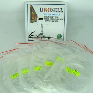 May include: A set of clear plastic bags containing strings for a Turkish string instrument called a Kanun. The bags are labelled with different string sizes. The image also includes a product information card with the brand name "UNOSELL DUPONT STRINGS" and the text "STRING SET FOR TURKISH STRING INSTRUMENT KANUN QANUN".