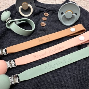 May include: Three personalized silicone pacifier clips with different colored silicone beads and clips. The clips are labeled with the names "Henry", "Hannah Kathleen", and "Maya Grace".