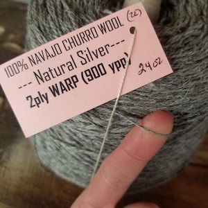 May include: A skein of 100% Navajo Churro wool yarn in a natural silver color. The label reads "100% Navajo Churro Wool (22) --- Natural Silver --- 2ply Warp (900 ypp) 24 oz".