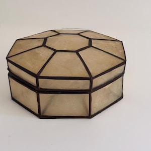 May include: An octagonal lidded box constructed from translucent, off-white shell panels joined by dark, thin metal soldering. The box features a flat top with a central octagonal panel surrounded by eight trapezoidal panels, and matching side panels.