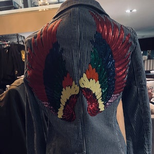 Blau-weißer Denim. Jacke mit multicored Pailletten-Engelsflügeln und Sternen 38