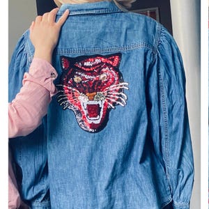 May include: A blue denim shirt with a red and black tiger applique on the back.