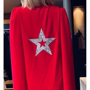May include: A red cape with a large silver glitter star on the back.