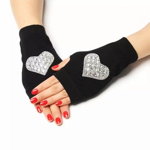 Könnte beinhalten: Ein Paar schwarze Fingerlose Handschuhe mit einem Strassstein-Herz-Design auf jedem Handschuh.