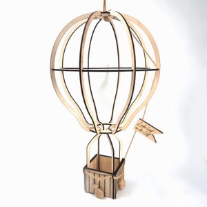 May include: A wooden hot air balloon with a basket and a small flag that says "Liebe liegt in der Luft".