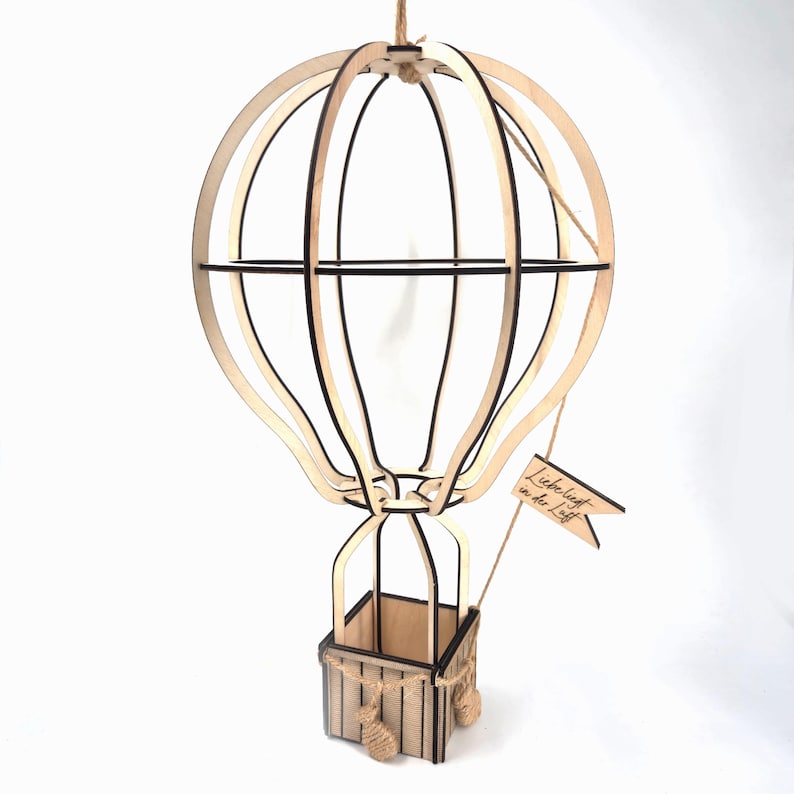 May include: A wooden hot air balloon with a basket and a small flag that says "Liebe liegt in der Luft".