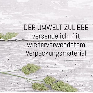 Puede incluir: Un fondo de madera blanqueada con una rama de hierba seca. El texto "DER UMWELT ZULIEBE versende ich mit wiederverwendetem Verpackungsmaterial" est&aacute; escrito en negro.