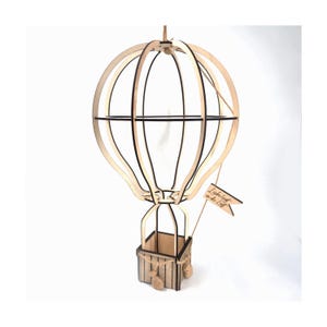 May include: A wooden hot air balloon with a basket and a small flag that says "Liebe geht in die Luft".