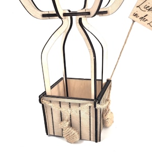 May include: A wooden hot air balloon with a basket made of wood and rope. The balloon is decorated with a sign that says "Liebe in der Luft".