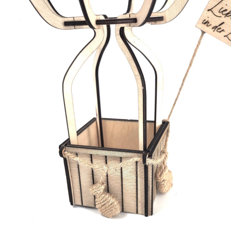 May include: A wooden hot air balloon with a basket made of wood and rope. The balloon is decorated with a sign that says "Liebe in der Luft".