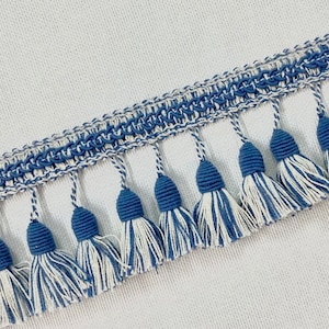 May include: Blue and white trim with a fringe of tassels. The tassels are made of a blue and white yarn.