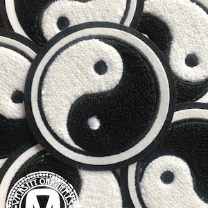 May include: Circular patches with a yin and yang design. The patches are black and white with a textured, embroidered appearance. Each patch has a black center dot and a white border. The patches are scattered across the image.