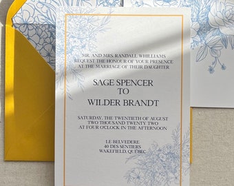 Op de afbeelding: Een huwelijksuitnodiging met een blauw bloemenontwerp en een gouden rand. De uitnodiging luidt "MR. AND MRS. RANDALL WHILLIAMS REQUEST THE HONOUR OF YOUR PRESENCE AT THE MARRIAGE OF THEIR DAUGHTER SAGE SPENCER TO WILDER BRANDT SATURDAY, THE TWENTIETH OF AUGUST TWO THOUSAND TWENTY TWO AT FOUR O'CLOCK IN THE AFTERNOON LE BELVEDERE 40 DES SENTIERS WAKEFIELD, QUEBEC"
