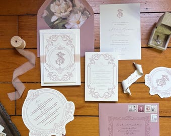 May include: A wedding stationery suite in pink and white, including invitation cards, an envelope with floral design, and a ring box. The invitations feature ornate borders and script text. A ribbon spool and stamps are also visible.