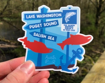 May include: A blue and red sticker with a salmon, anchor, and signposts pointing to Lake Washington, Puget Sound, and Salish Sea. The text "This salmon spawning stream is in your care" is on the sticker.