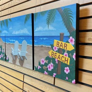 May include: A three-piece beach scene painting set. The paintings feature a blue ocean, white sand, palm trees, and two white chairs. The third painting features a sign that says "Bar" and "Beach" with pink flowers.