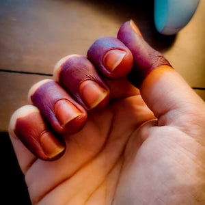 Woman hand with deep red-stained fingertips using Amarya Henna Cones