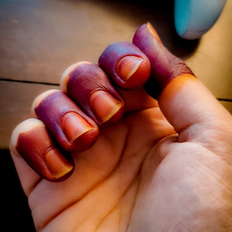 Woman hand with deep red-stained fingertips using Amarya Henna Cones