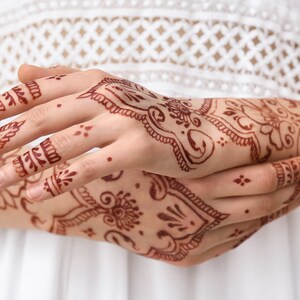 Woman arms adorned with intricate henna designs. Can be achieved with Amarya Henna cones.