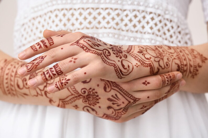Woman arms adorned with intricate henna designs. Can be achieved with Amarya Henna cones.