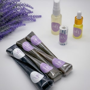 May include: Four henna cones, two brown and two black, with a white label that says "Up" and a purple circle with the text "ah" in white.  Two bottles, one clear with a white spray nozzle and the other amber with a dropper, both with a purple circle label with the text "ah" in white.  A roll of medical tape with the text "ah" in white on a purple circle label.