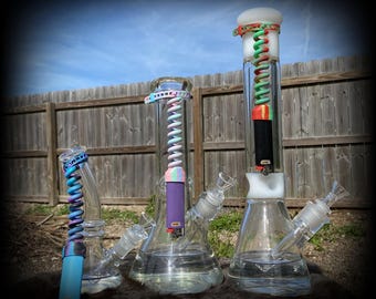 May include: Three glass bongs with colorful silicone coil attachments. The bongs are different sizes and have a clear glass body. The coils are in various colors, including pink, blue, green, and red.